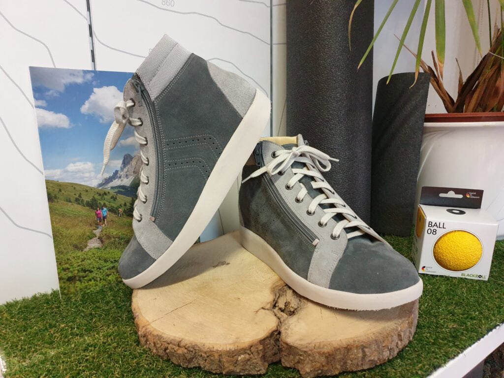 Schuh-Design, Sportschuh, High Top, Grau mit seitlicher Reißverschluss, Photo mit Natur- und Bergmotiv, Präsentation auf Holzscheibe, dazu Yoga-Matte und Tennisball, geeignet für Outdoor und Lifestyle.