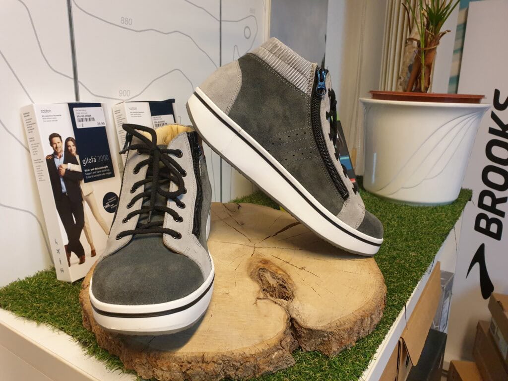 Sneaker auf Holzstamm als Produktpräsentation, modische Sportschuhe für Komfort und Gesundheit, geeignet für Alltag und Freizeit, stilvolle Schuhe mit zipper und Schnürung, optimaler Tragekomfort, orthopädische Schuhe.