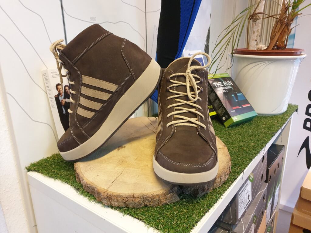 Verschleißfeste braune Sportschuhe mit bequemer Sohle, auf einem Holzstück mit künstlichem Rasen, ideal für Alltag und Freizeit.